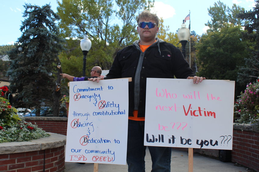 Clark Zimmerman, grandson of Idaho Springs' Michael Clark, holds signs during Saturday's rally for victims of the Idaho Springs Police Department in Citizens Park. Michael Clark is still experiencing serious medical problems after being stunned by ISPD officers on May 30, and his grandson said he doesn't want the same situation to happen to anyone else.